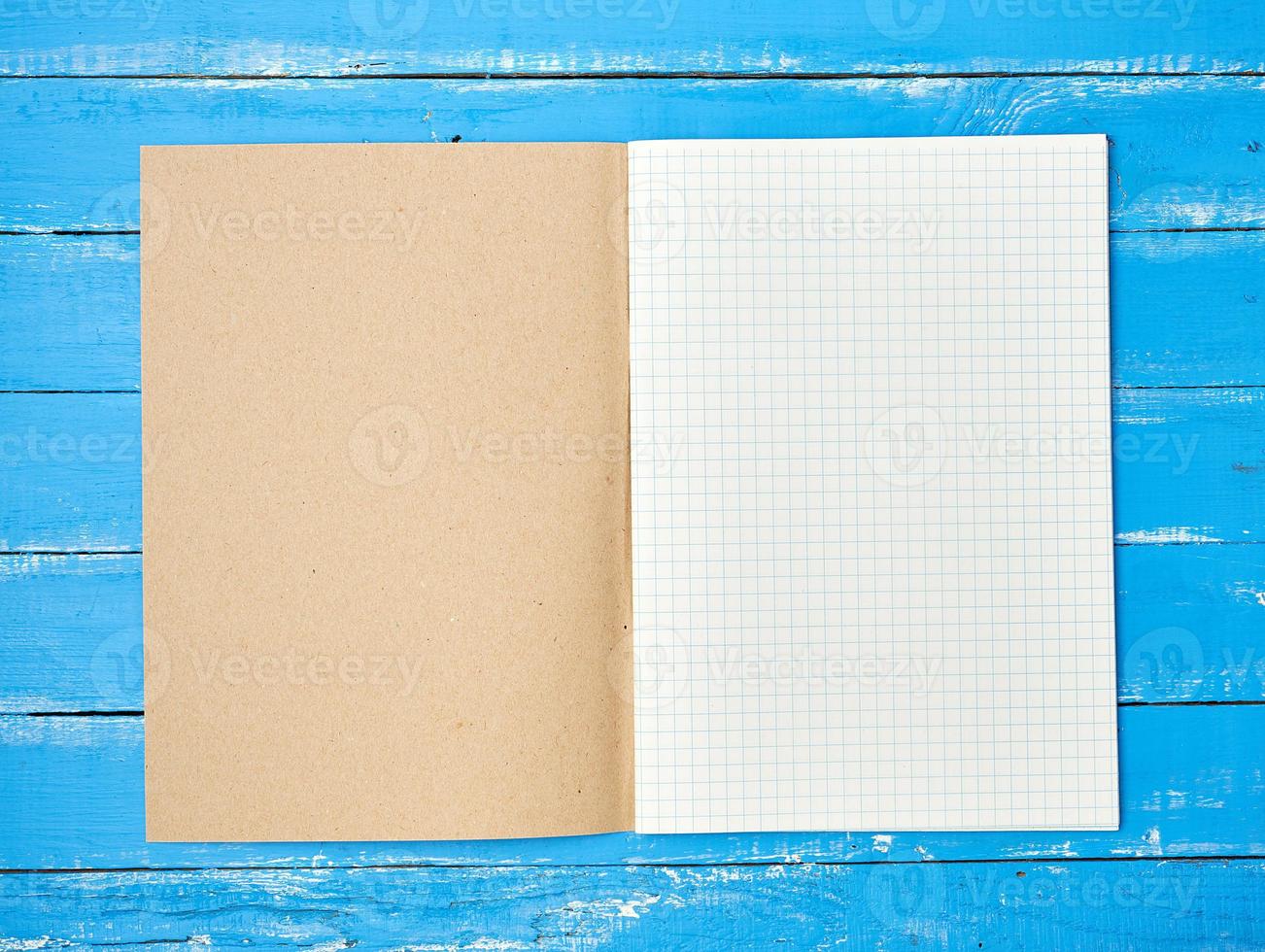 open checked school notebook on blue wooden background photo