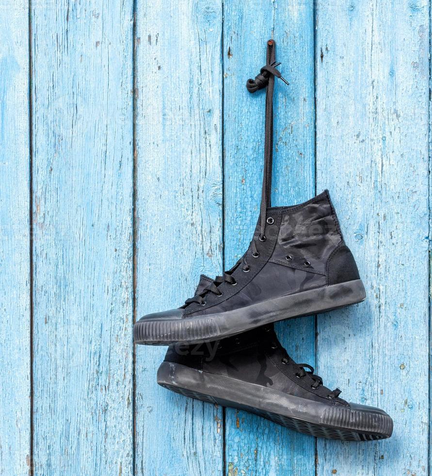 black pair of worn men's textile sneakers hangs photo