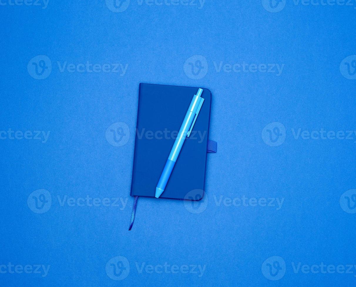 closed notebook and blue pen on a colored background photo