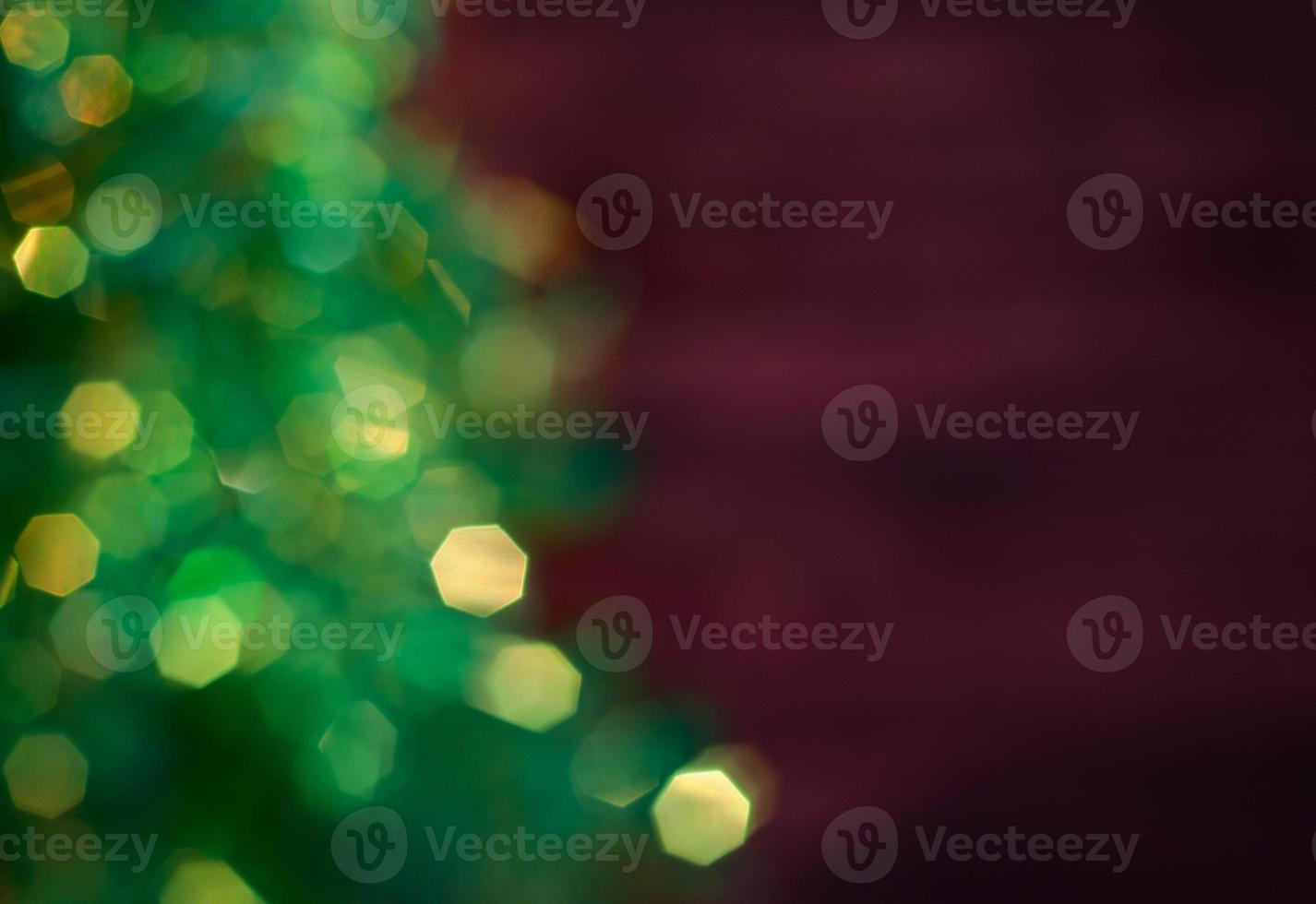 Blurred Christmas tree with garland, green bokeh on a dark red background blurred photo