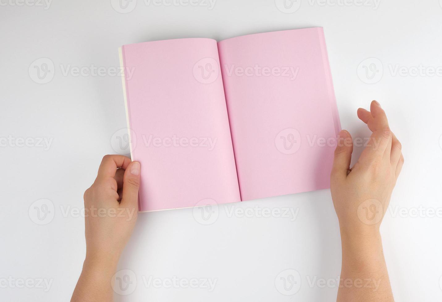 two female hands holding open notepad with clean pink sheets photo