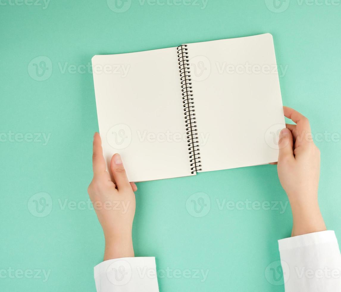 two female hands holding open notepad with clean sheets photo