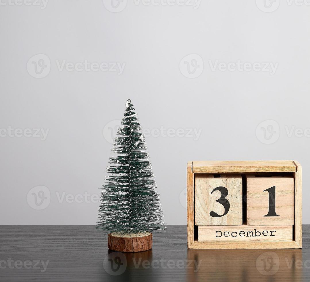 wooden calendar of cubes with the date of December 31 and green tree photo
