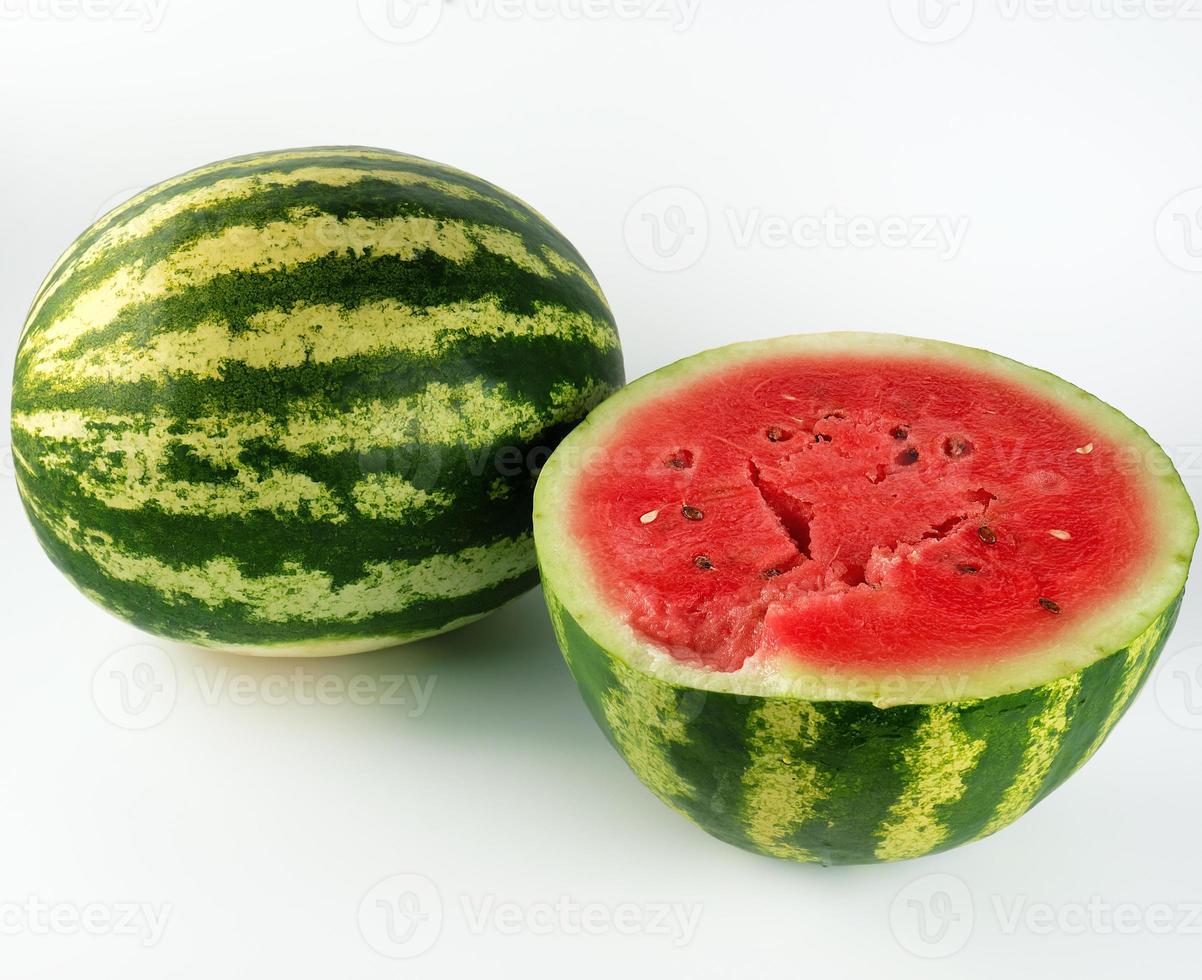 half ripe watermelon with red juicy pulp and seeds and a whole green photo