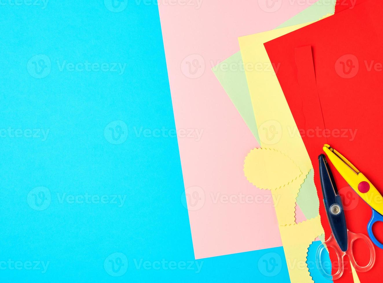 a pair of plastic scissors and colored paper for cutting figures photo