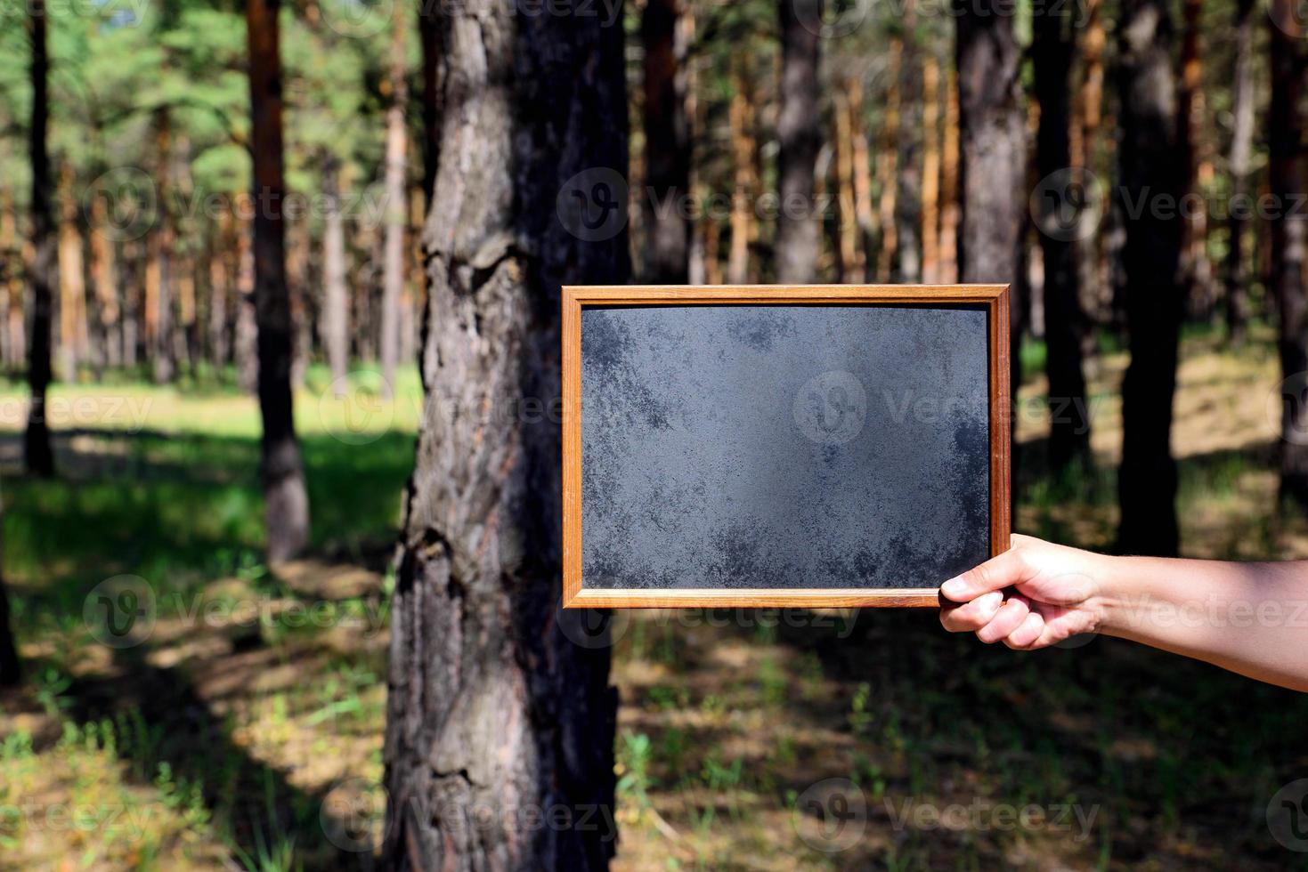 Empty black chalk board in the right hand of a man photo