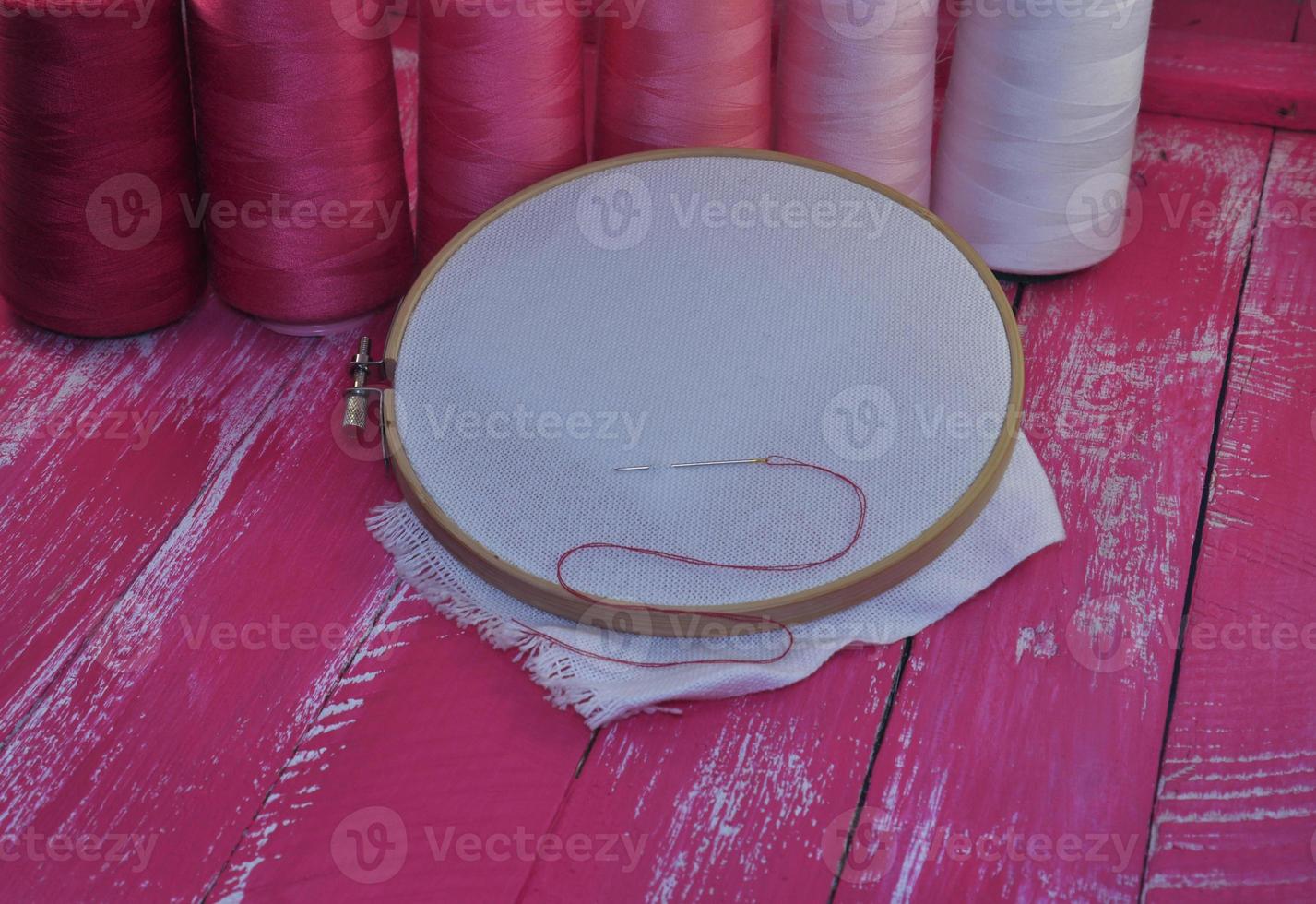 canvas in wooden hoop for embroidery on a pink background photo