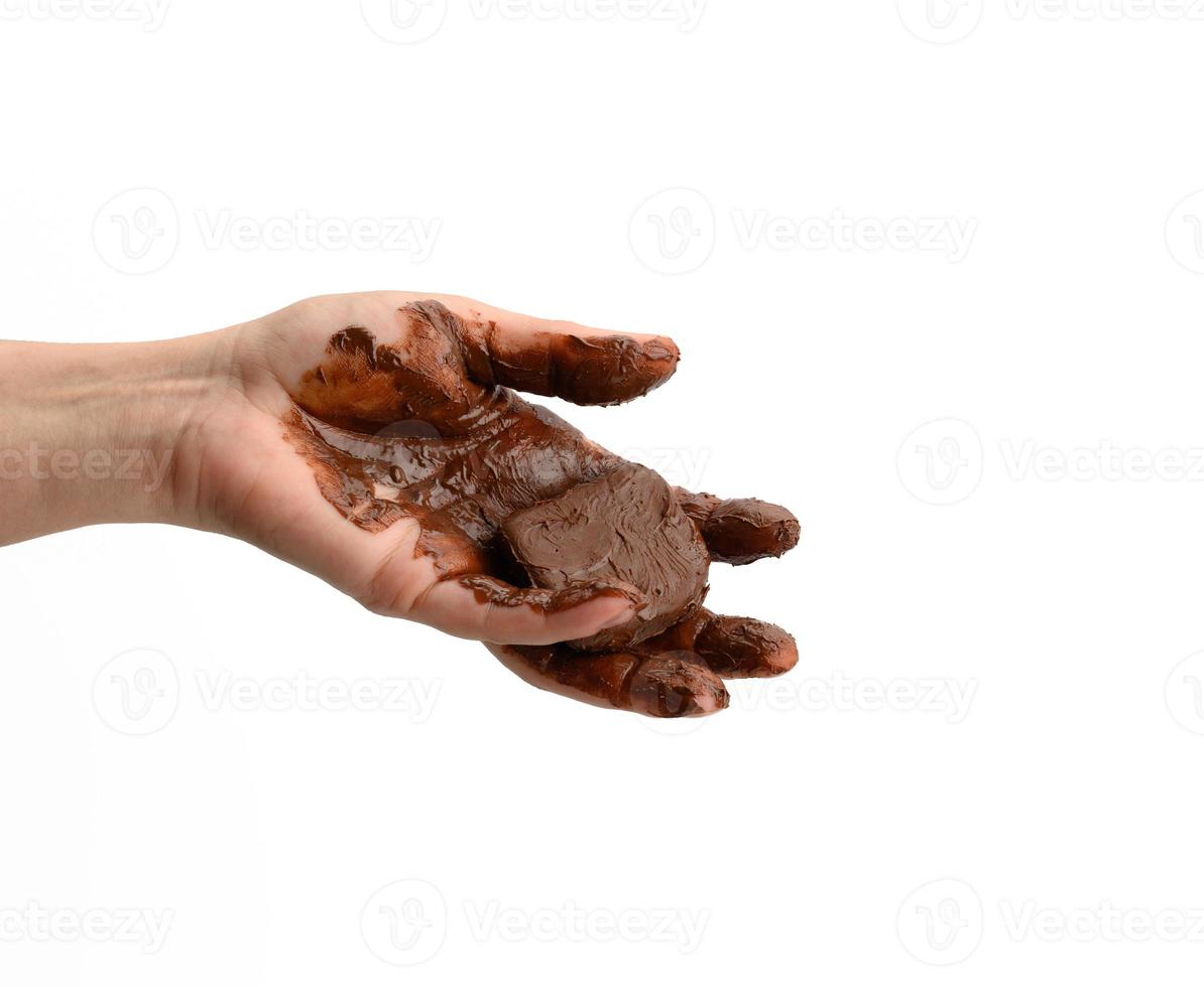 female hand holding a melted piece of dark chocolate, hand smeared with chocolate on a white background photo
