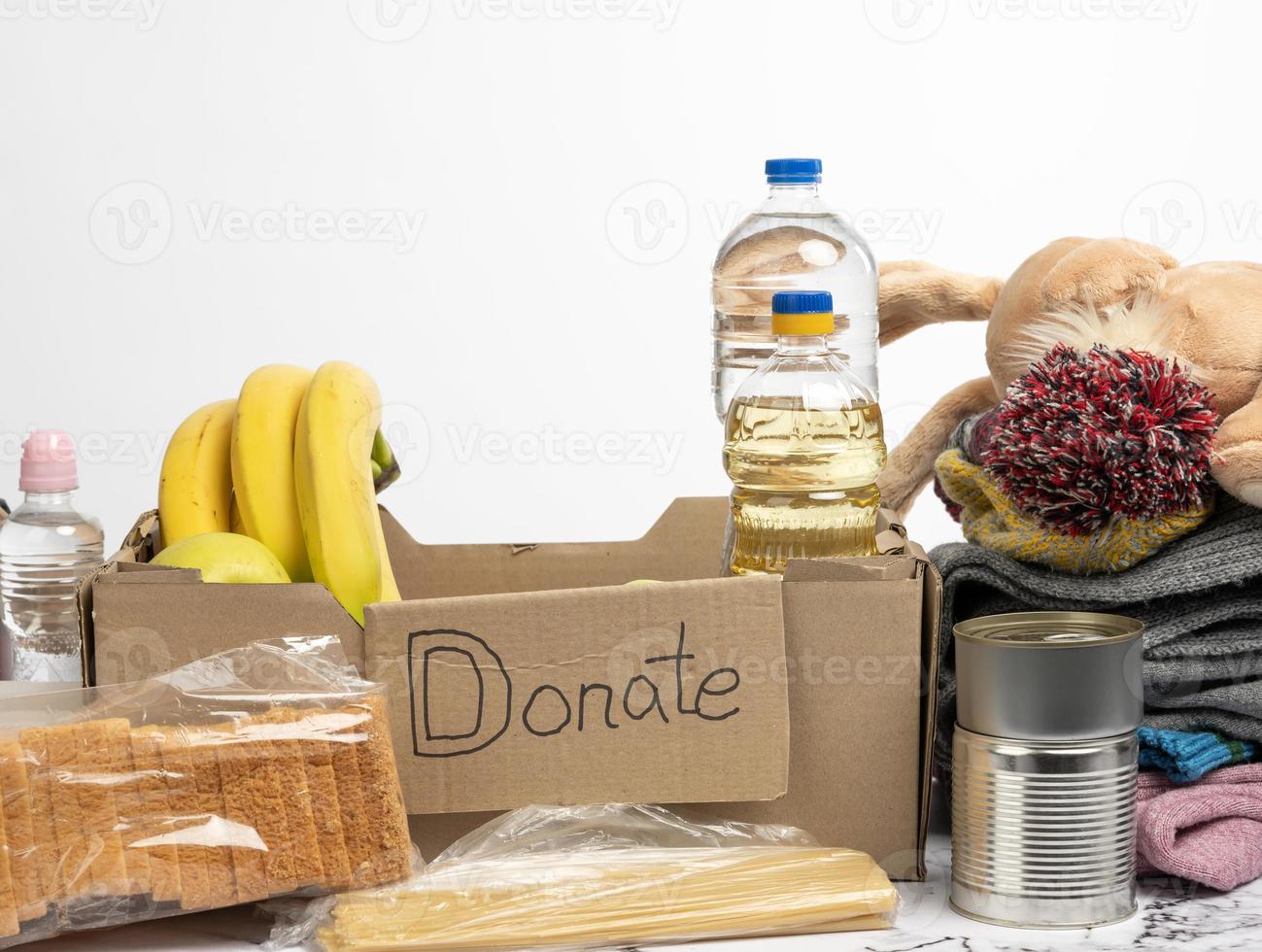 cardboard box with various products, fruits, pasta, sunflower oil in a plastic bottle and preservation photo