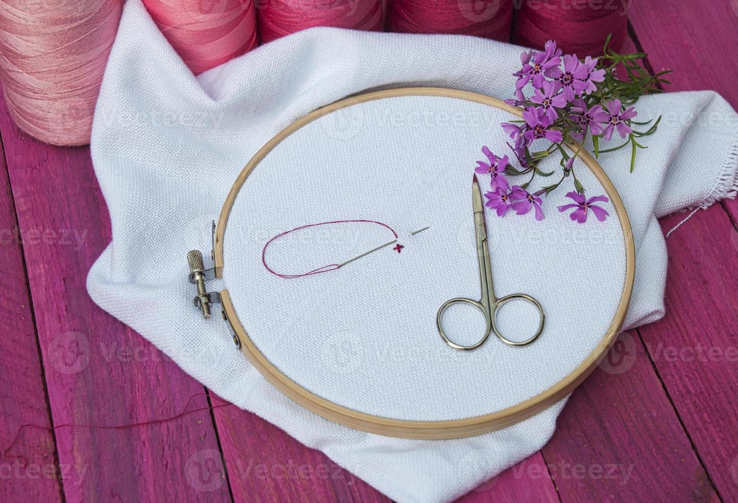 Pink thread and white fabric in the wooden embroidery frame for needlework photo