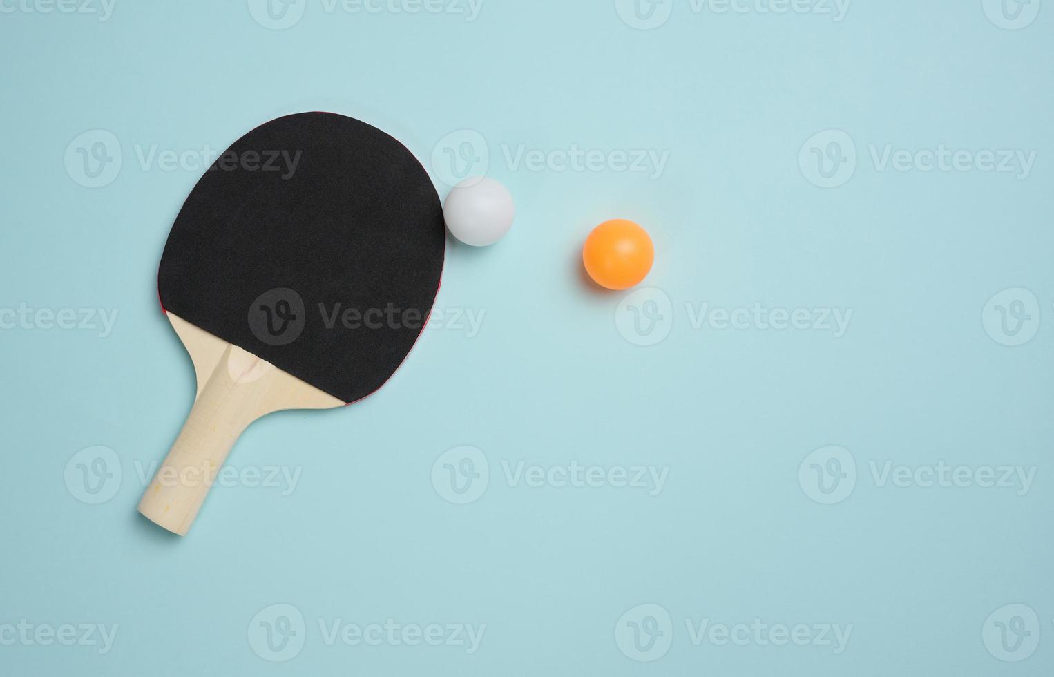 Wooden tennis racket for ping pong and a plastic ball on a blue background photo