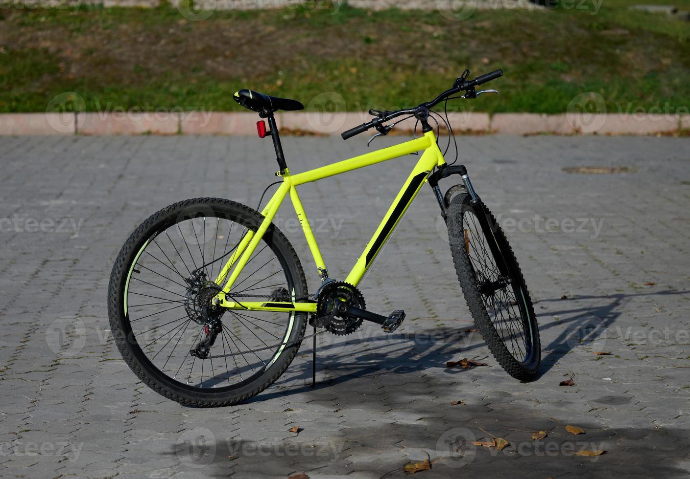 A yellow bicycle stands in the middle of the street on an autumn day photo