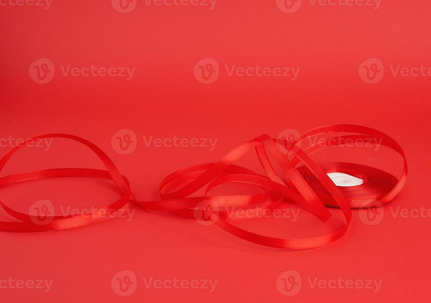 twisted red silk shiny ribbon on a red background photo