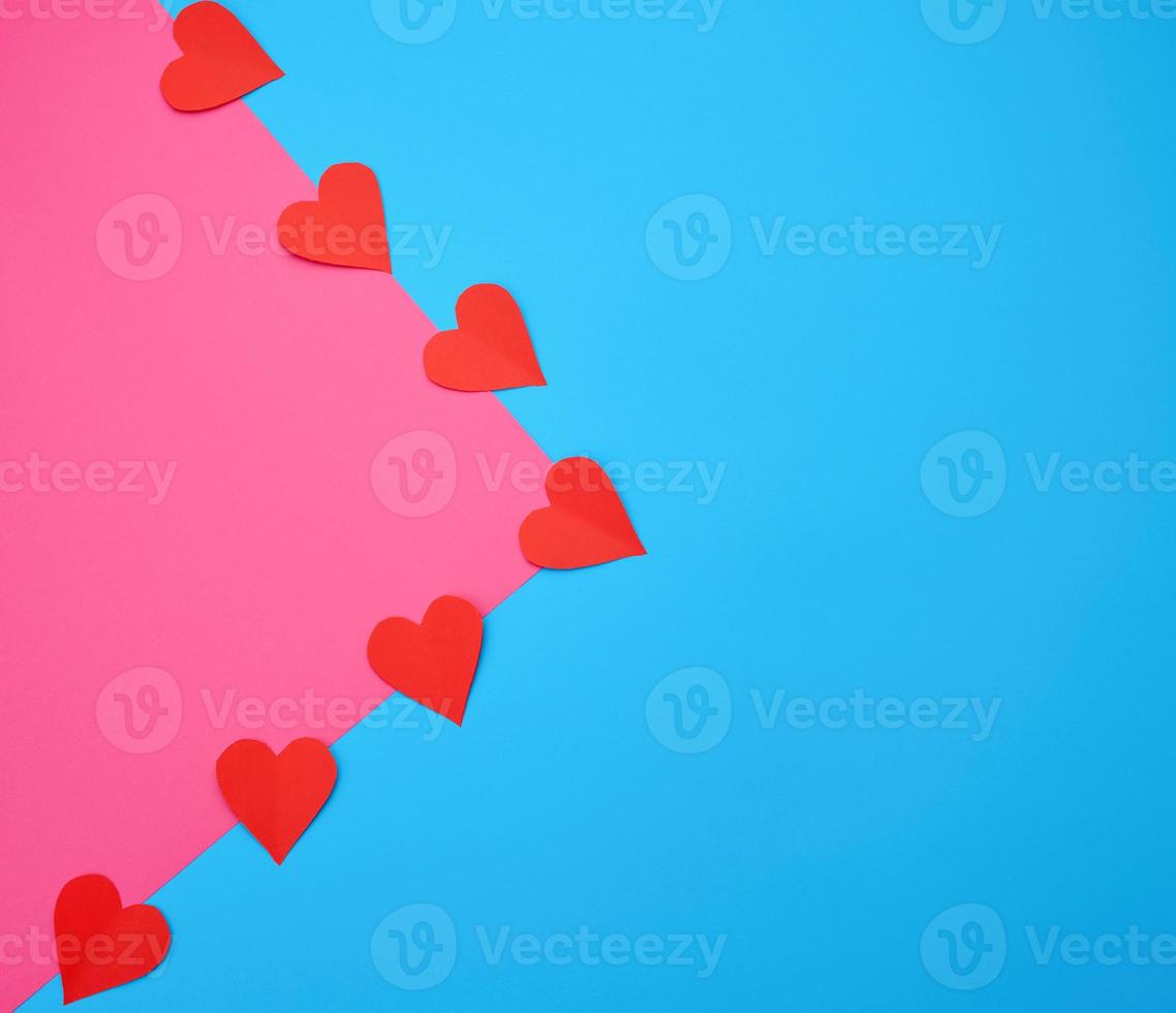 hearts cut out of red paper on a blue pink background photo