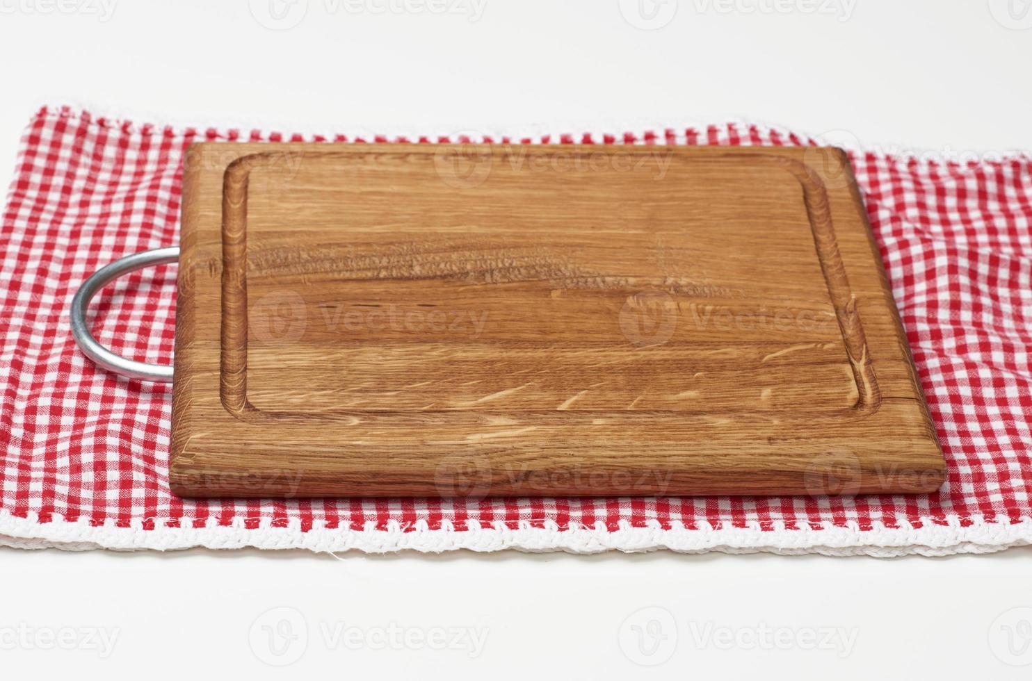 empty rectangular wooden kitchen cutting board and red towel in a white cage on a white table, top view photo