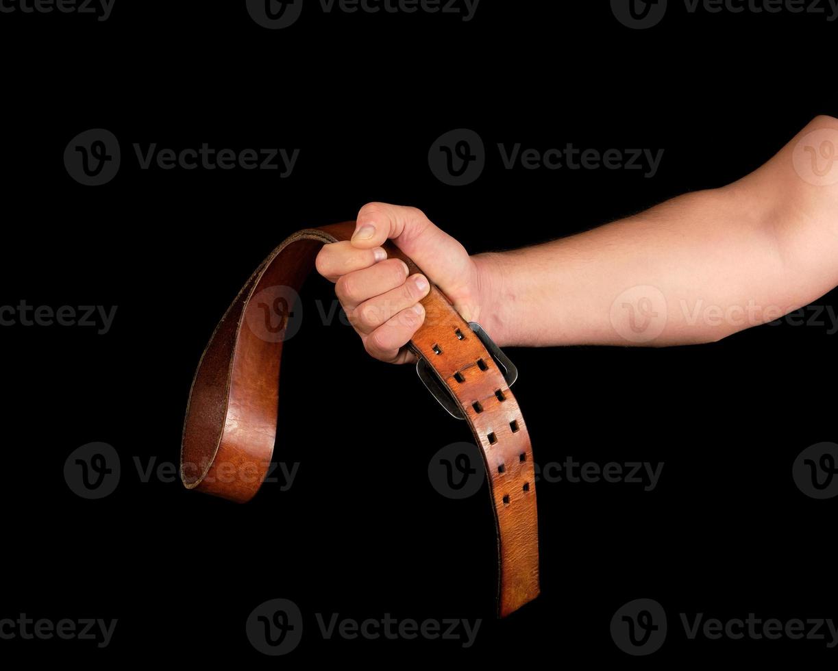 brown leather belt with an iron buckle in a man's hand photo