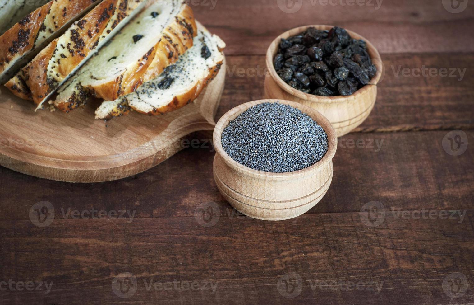 Poppy seeds and raisins in wooden bowls on a brown surface photo