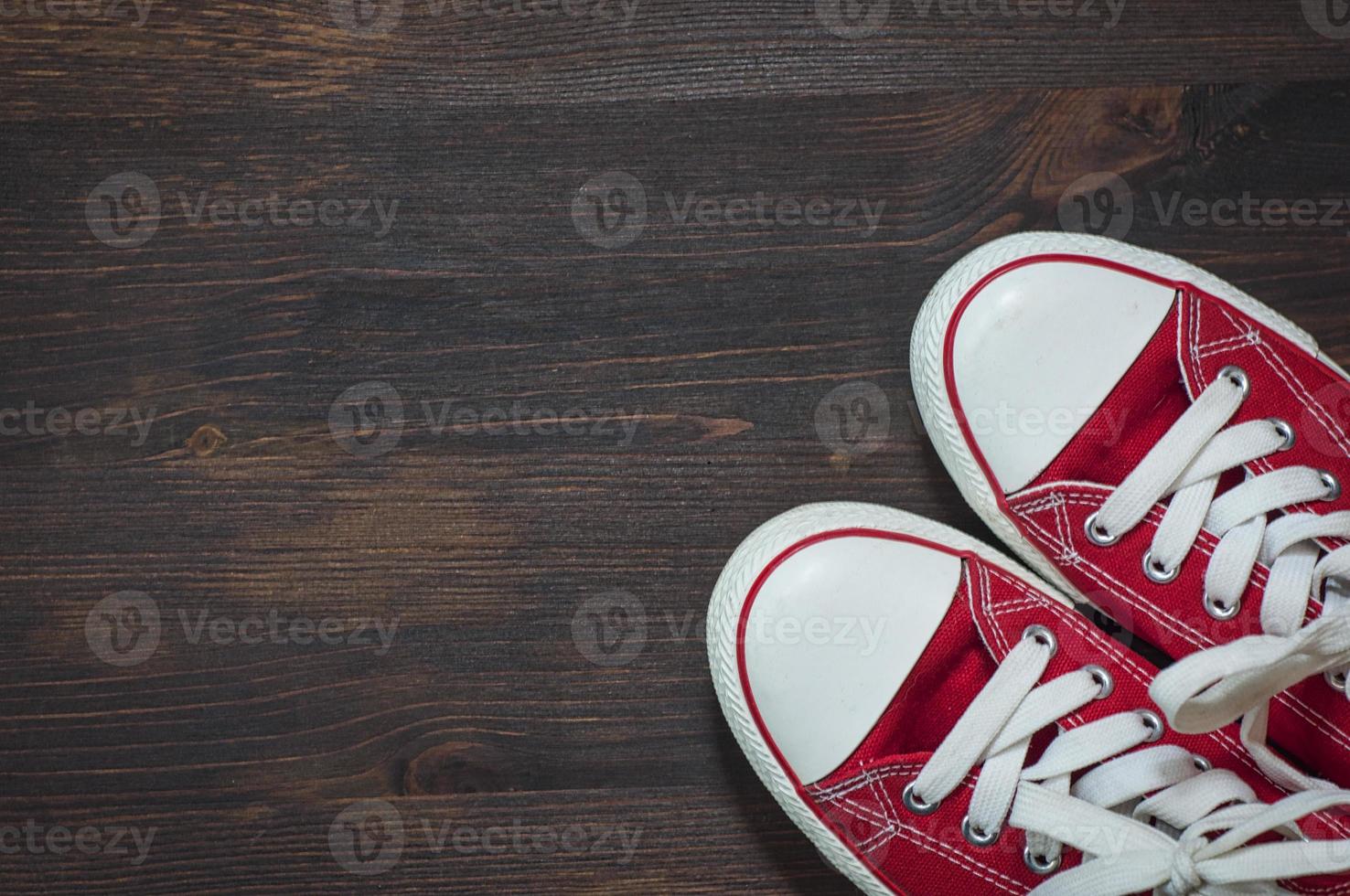 pair of red sneakers on a brown wooden surface photo