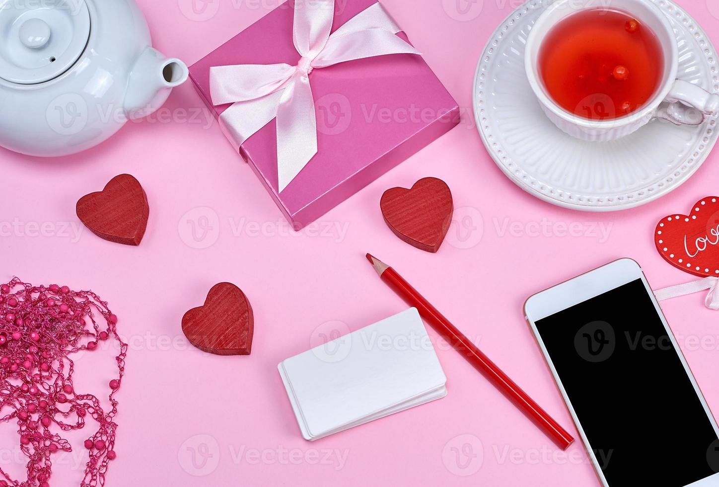empty white paper business cards, smartphone and herbal tea on a pink background photo