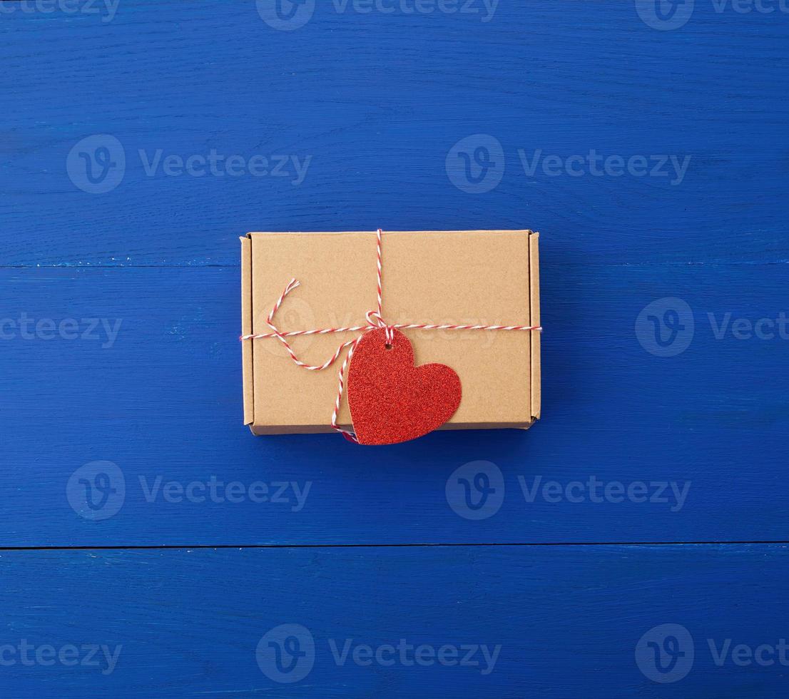 rectangular brown box with a gift and a red paper heart tied to a rope photo