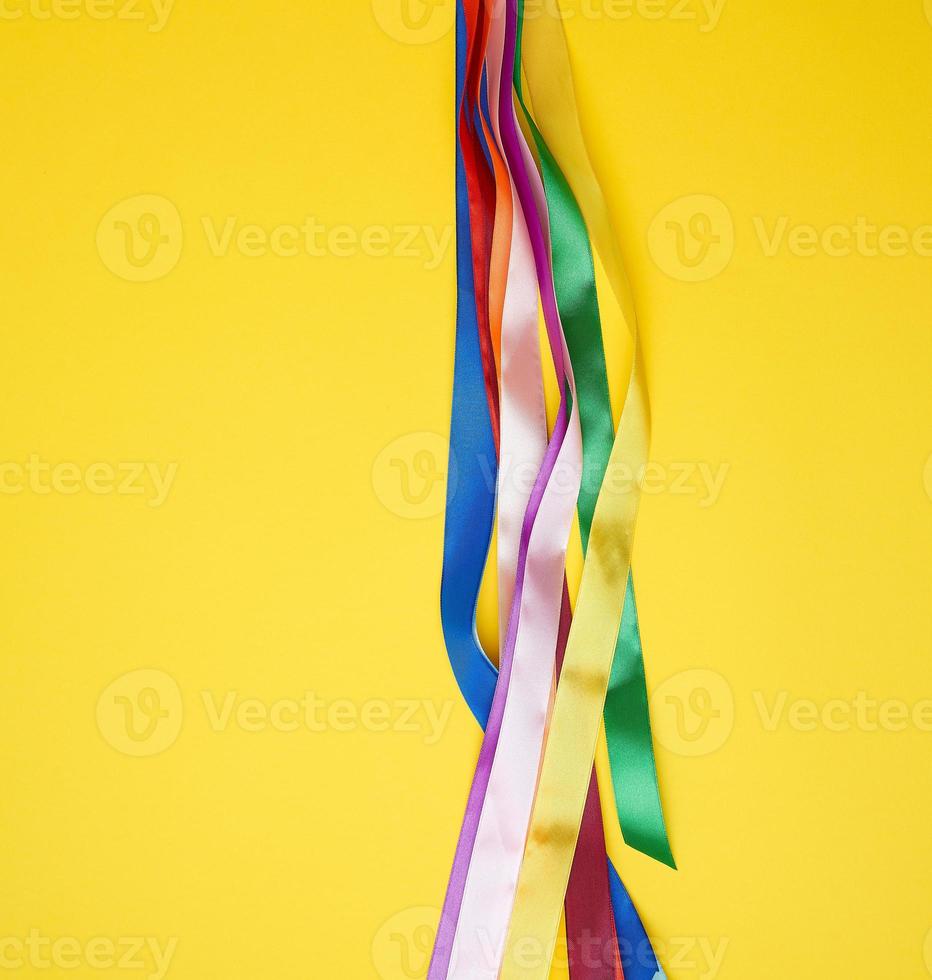 many silk multi-colored ribbons on a yellow background photo