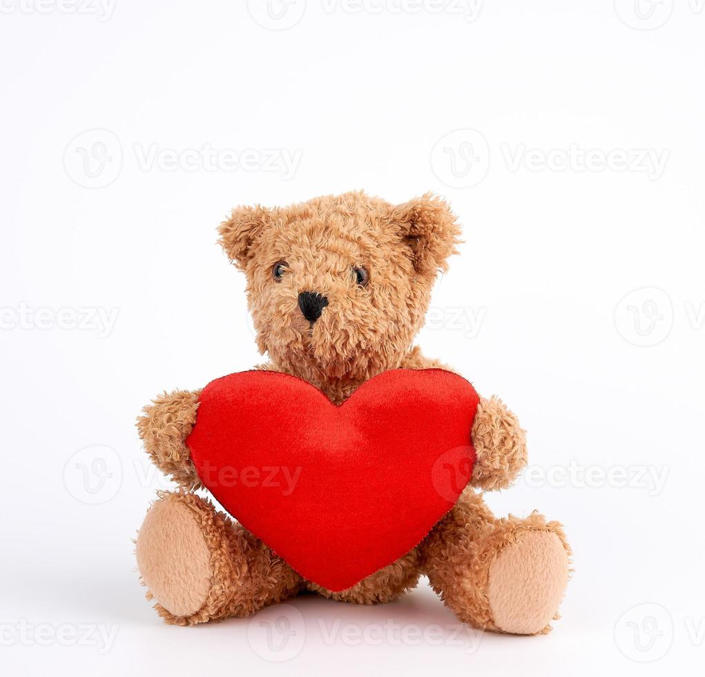 lindo oso de peluche marrón sosteniendo un gran corazón rojo sobre un fondo blanco foto