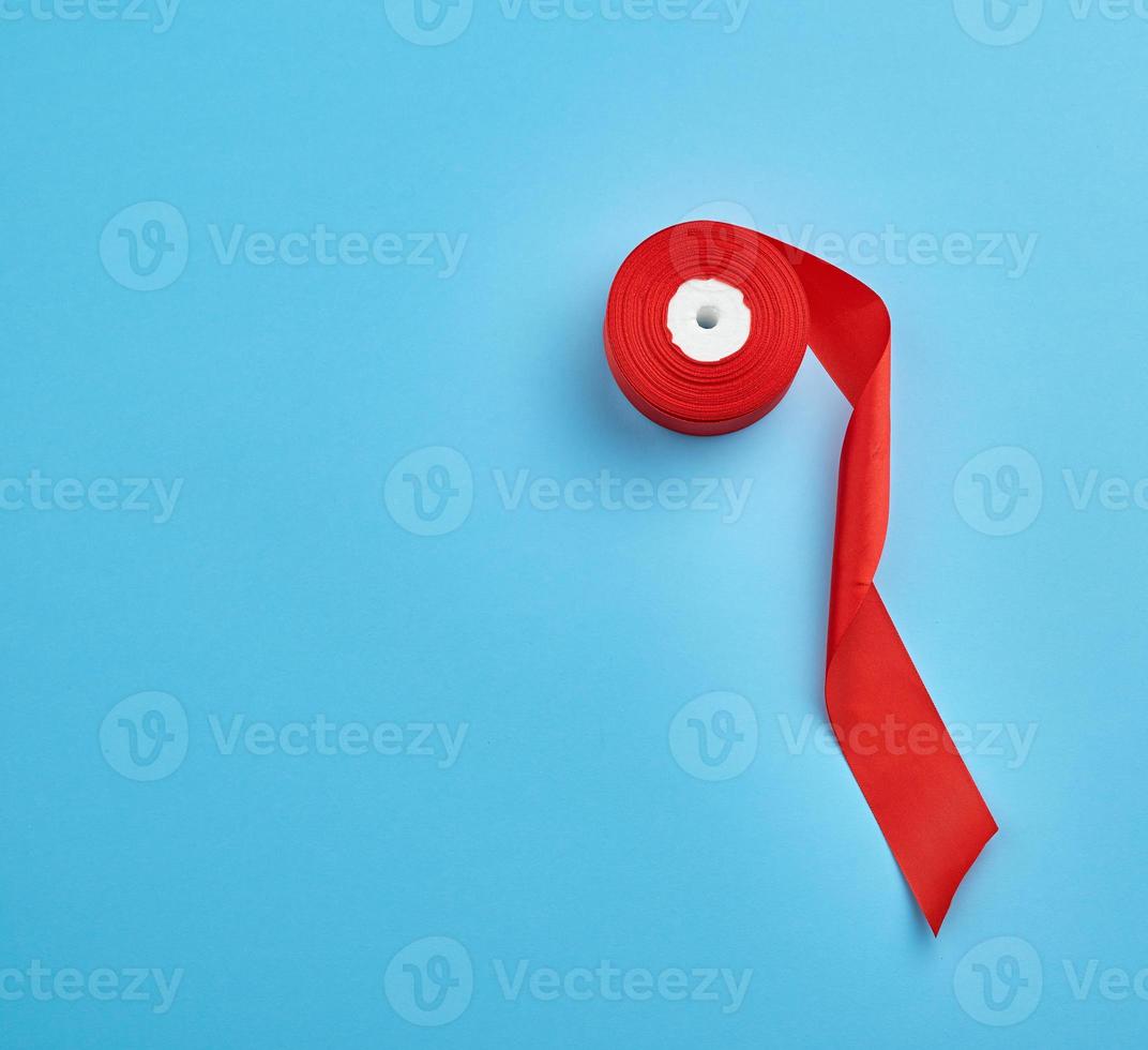 spools with red satin ribbon on a blue background photo