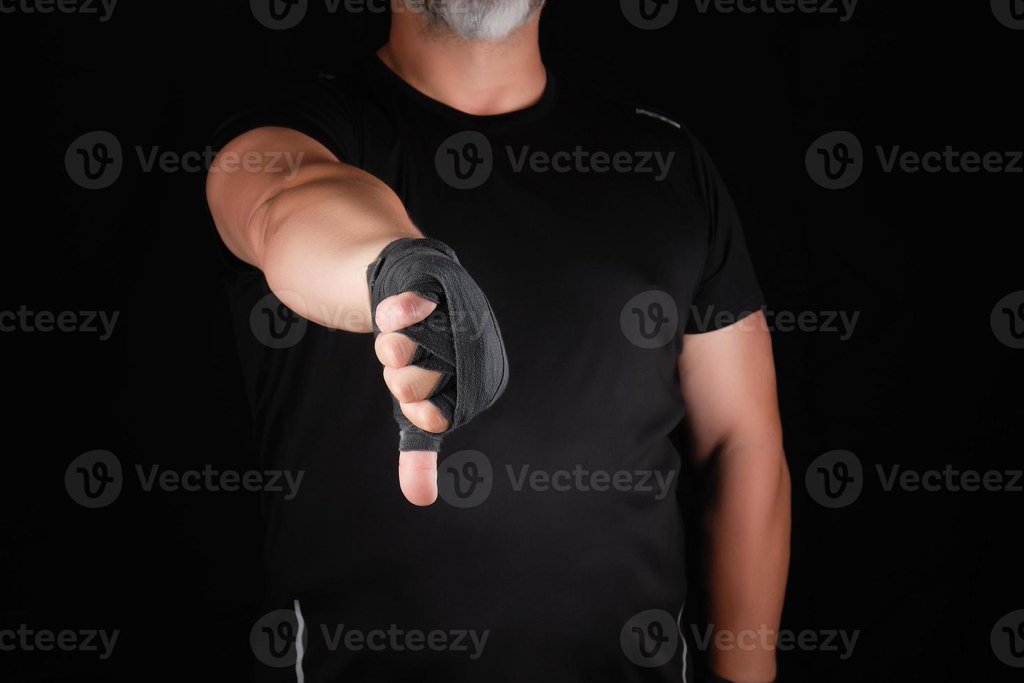 adult athlete in black uniform and hands rewound with textile bandage shows gesture dislike photo