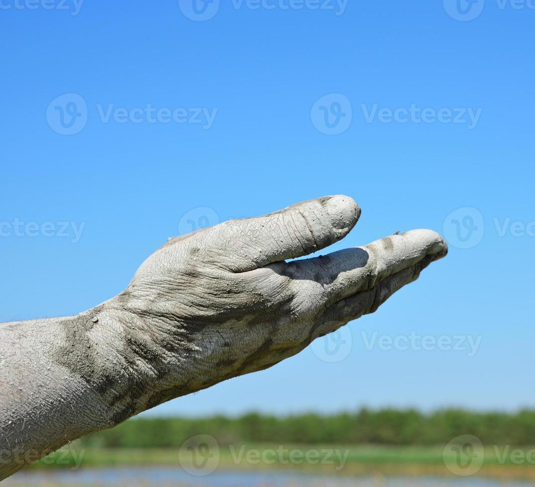 Man's hand in the mud extended forward photo