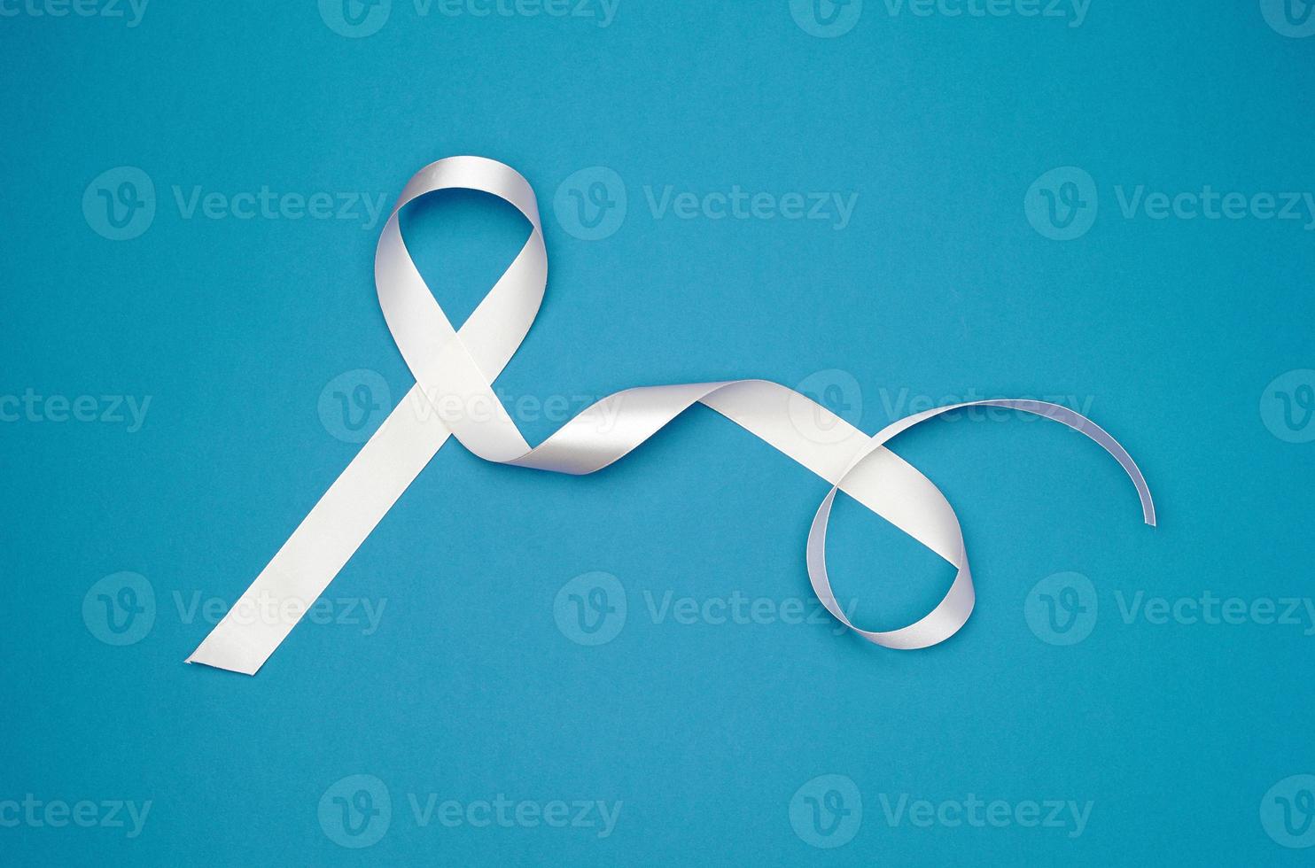 white silk thin ribbon twisted on a blue background photo