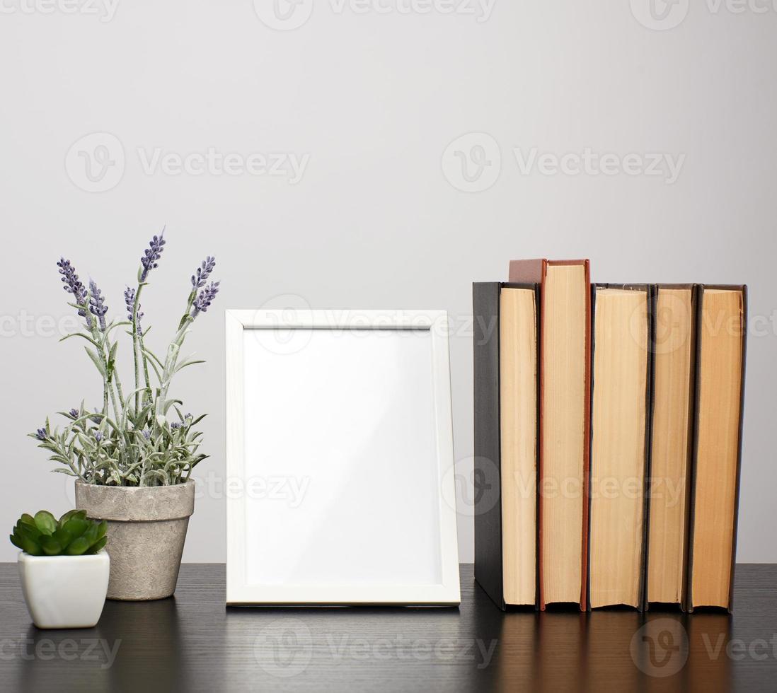 empty white photo frame, stack of books and a pot of growing lavender