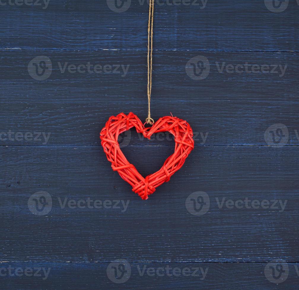 corazón decorativo de mimbre rojo colgando de una cuerda marrón foto