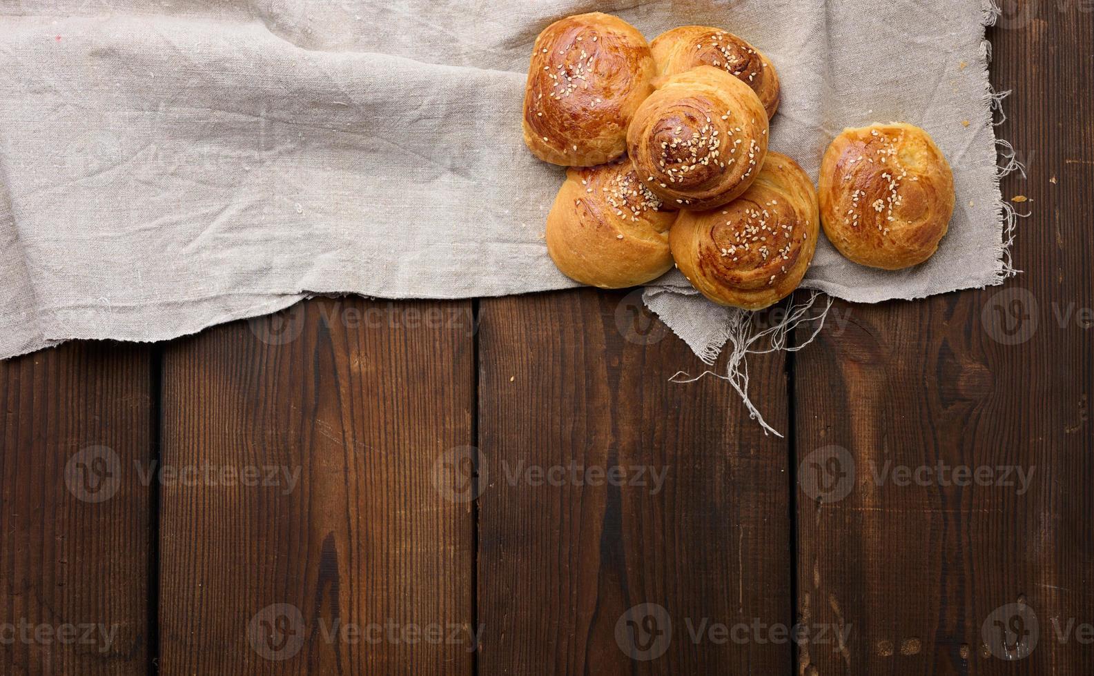 Baked round buns on a wooden table, top view photo