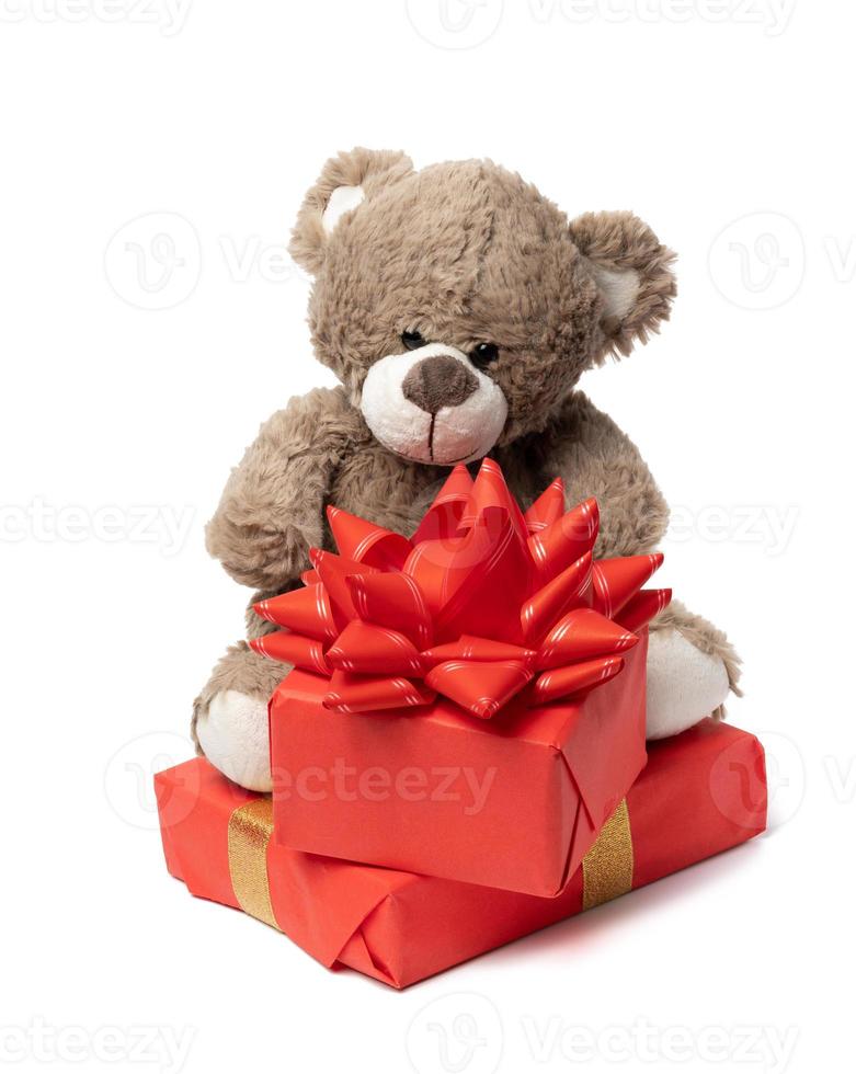 cute brown teddy bear and box wrapped in paper and red silk ribbon on white background. Prize and congratulations photo