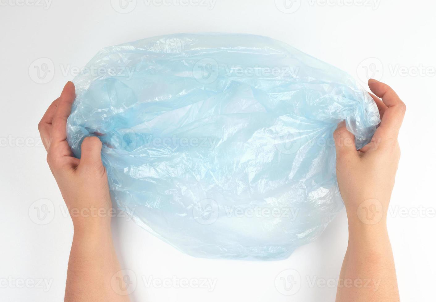 blue plastic garbage bag in female hands on a white background photo