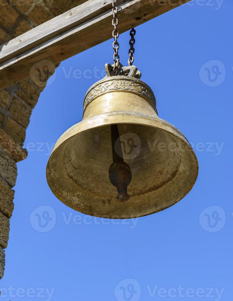 a large copper bell hanging on a wooden crossbeam photo