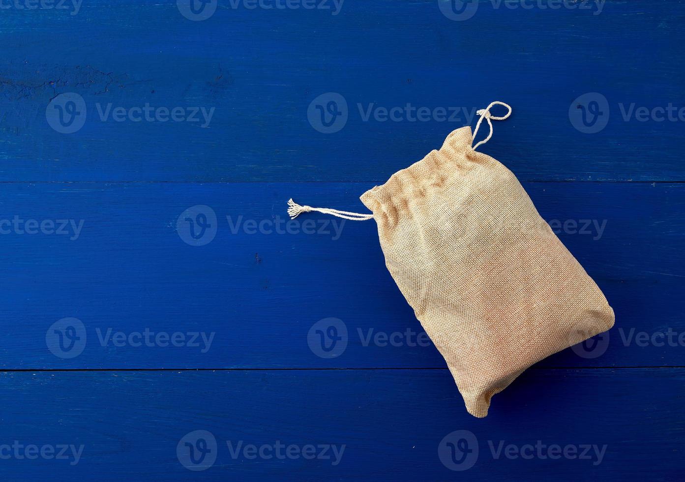 small full canvas bag with ties, blue wooden background photo