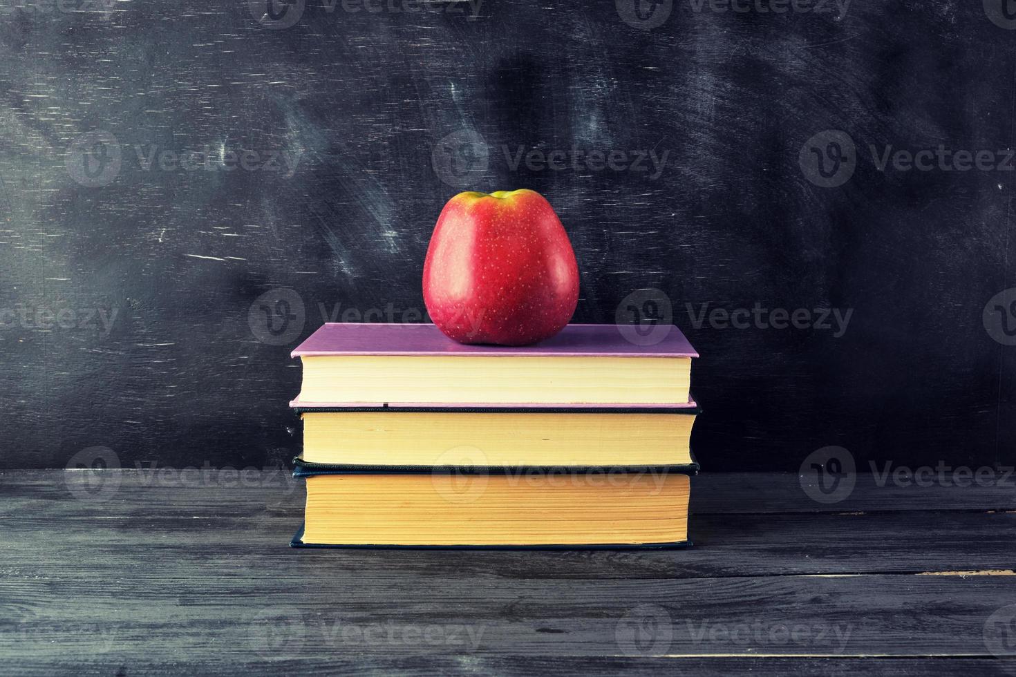 red ripe apple lies on a stack of books photo