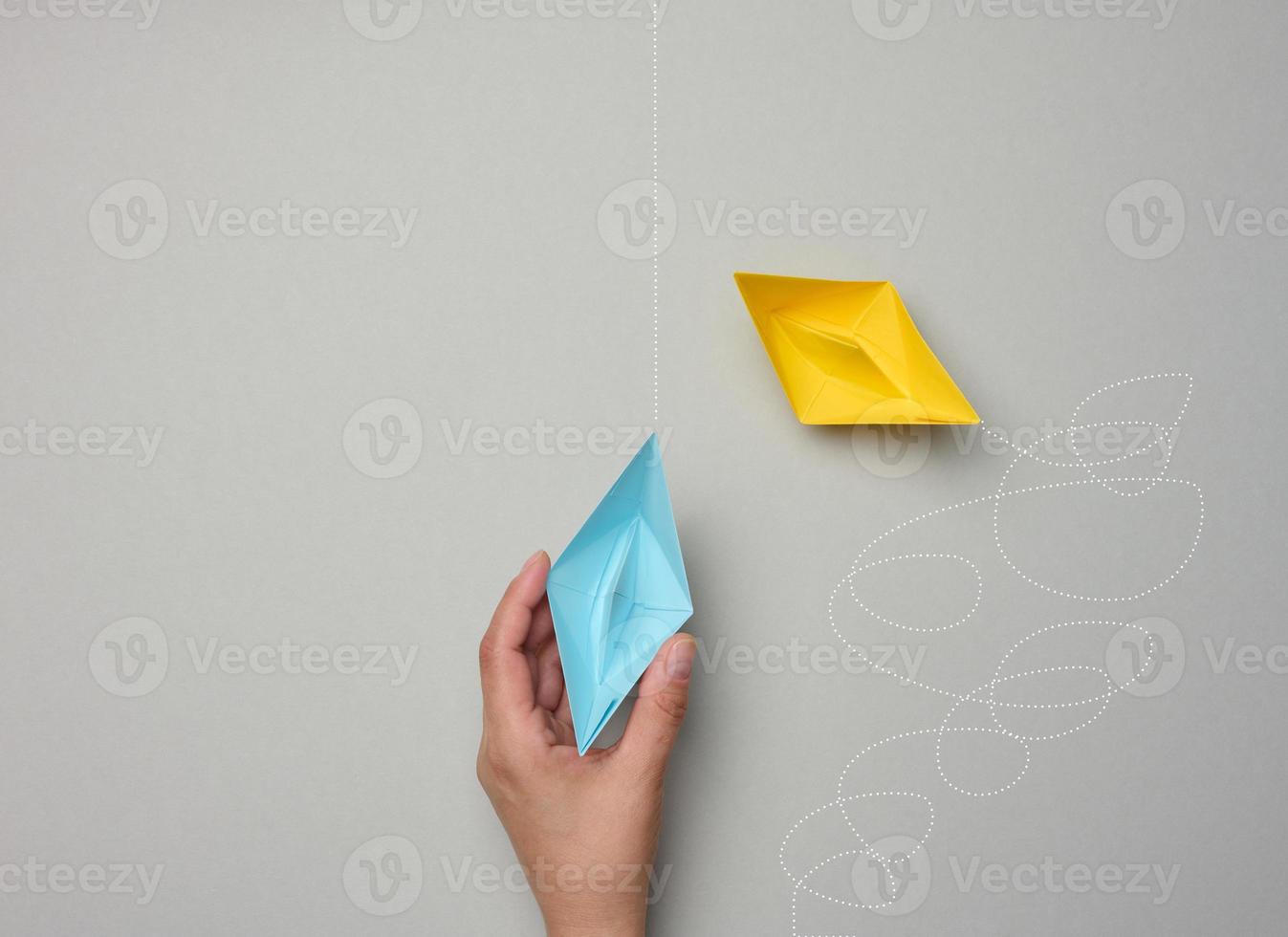 Paper boats with different trajectories on a gray background. The concept of extraordinary thinking photo