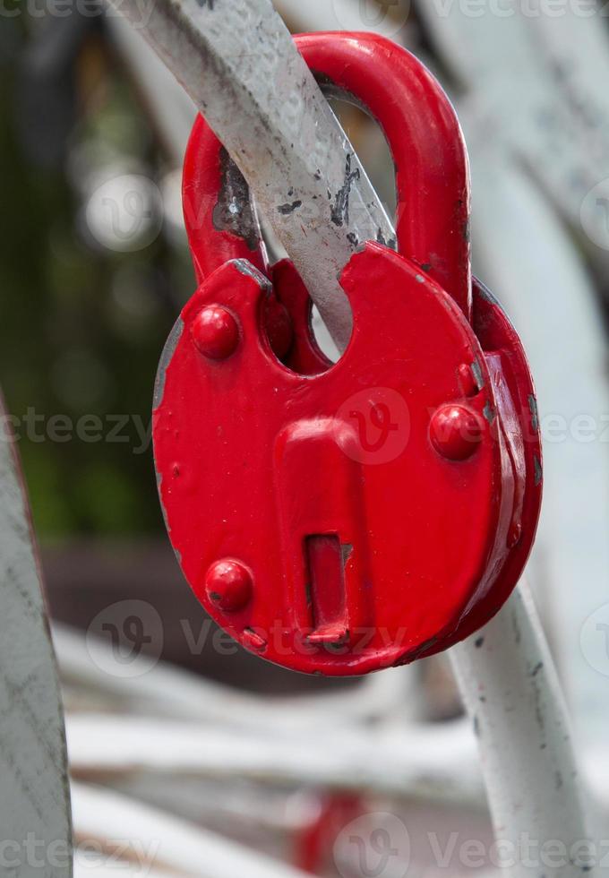 candado de hierro rojo en una cerca blanca foto