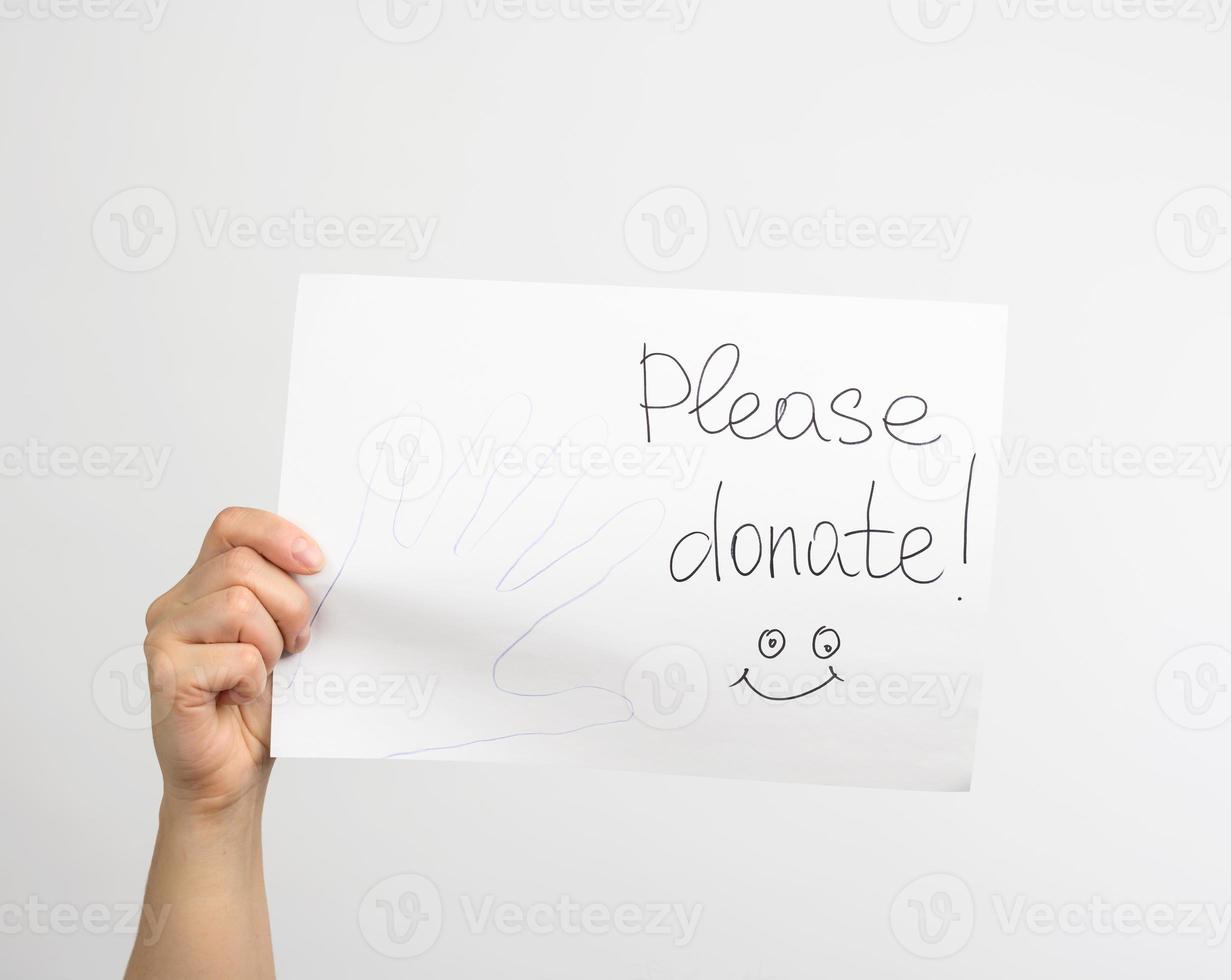 female hand holding a piece of paper with the inscription please donate photo