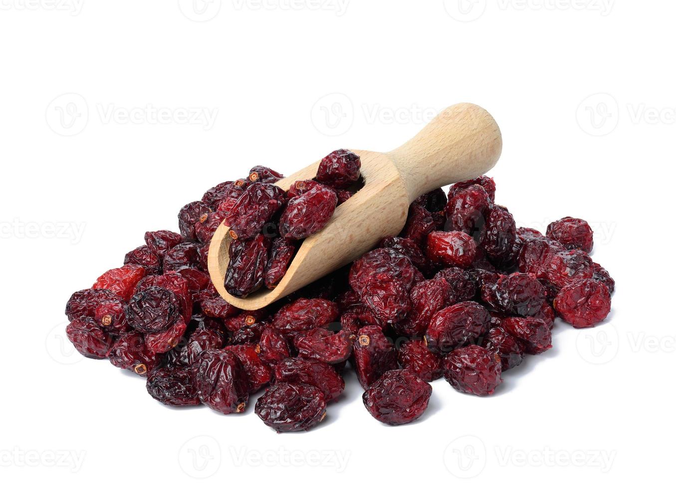 a bunch of dried cranberries in a wooden spoon on a white background. Delicious berry photo