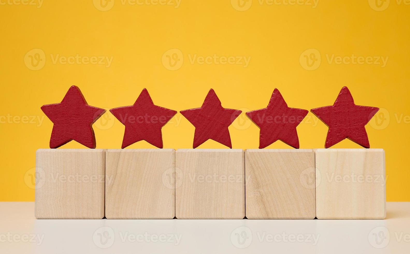 Five stars on wooden cubes, yellow background. Service evaluation concept photo