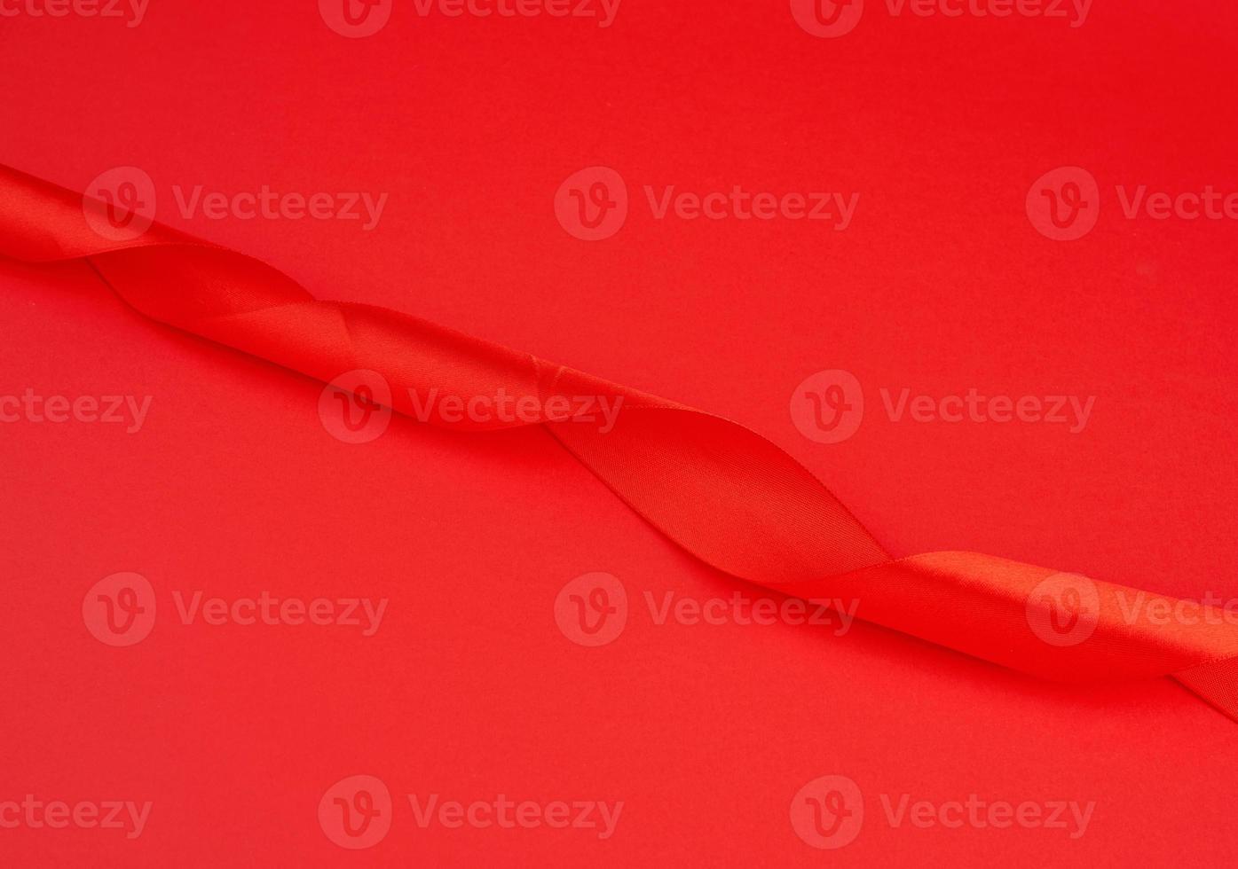 twisted red silk shiny ribbon on a red background, festive design element photo