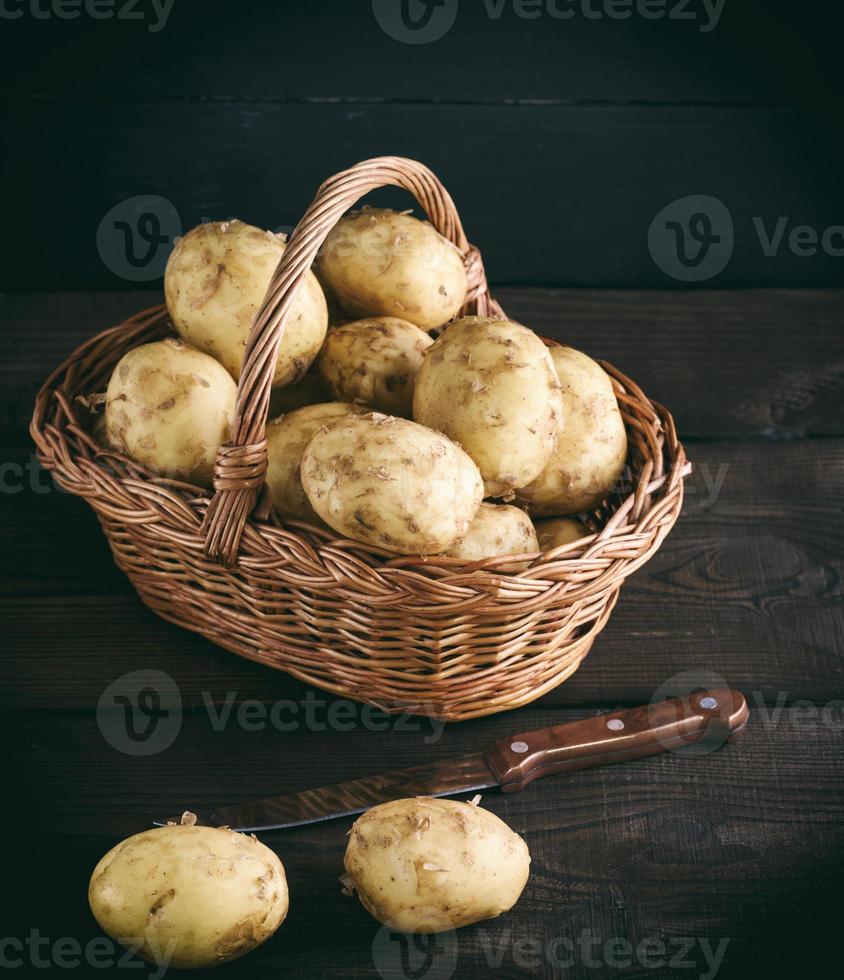 patatas frescas jóvenes en una cáscara yacía en una cesta de mimbre marrón foto
