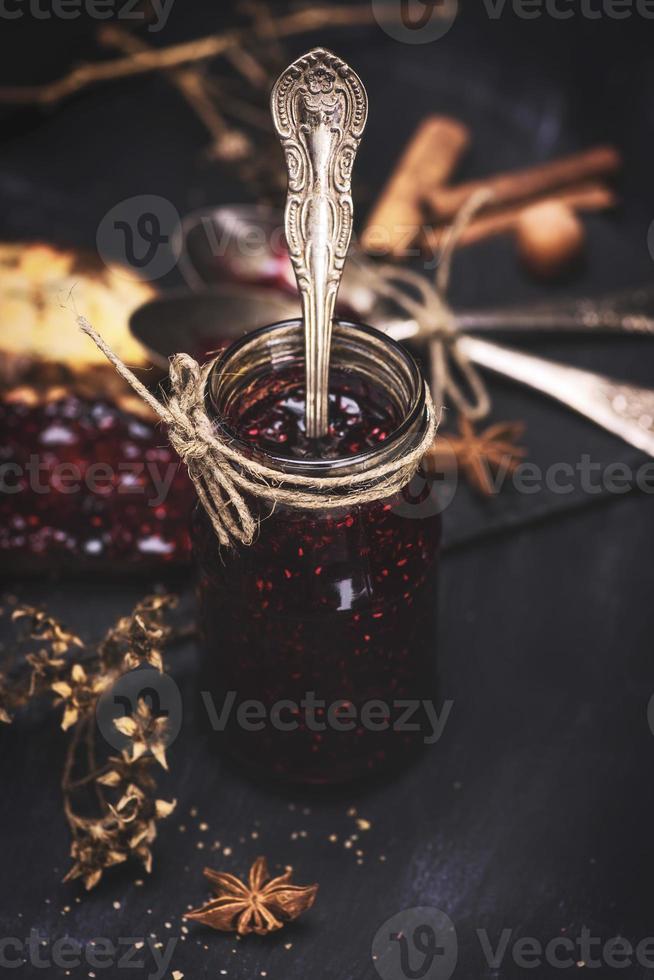 mermelada de frambuesa en un frasco de vidrio con una cuchara de hierro foto