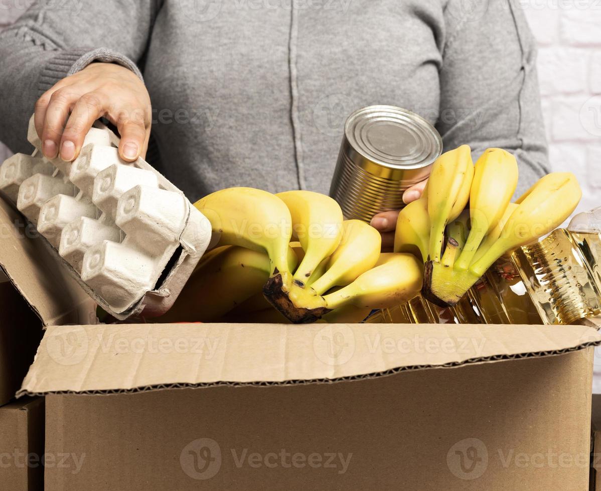 woman collects food, fruits and things in a cardboard box photo