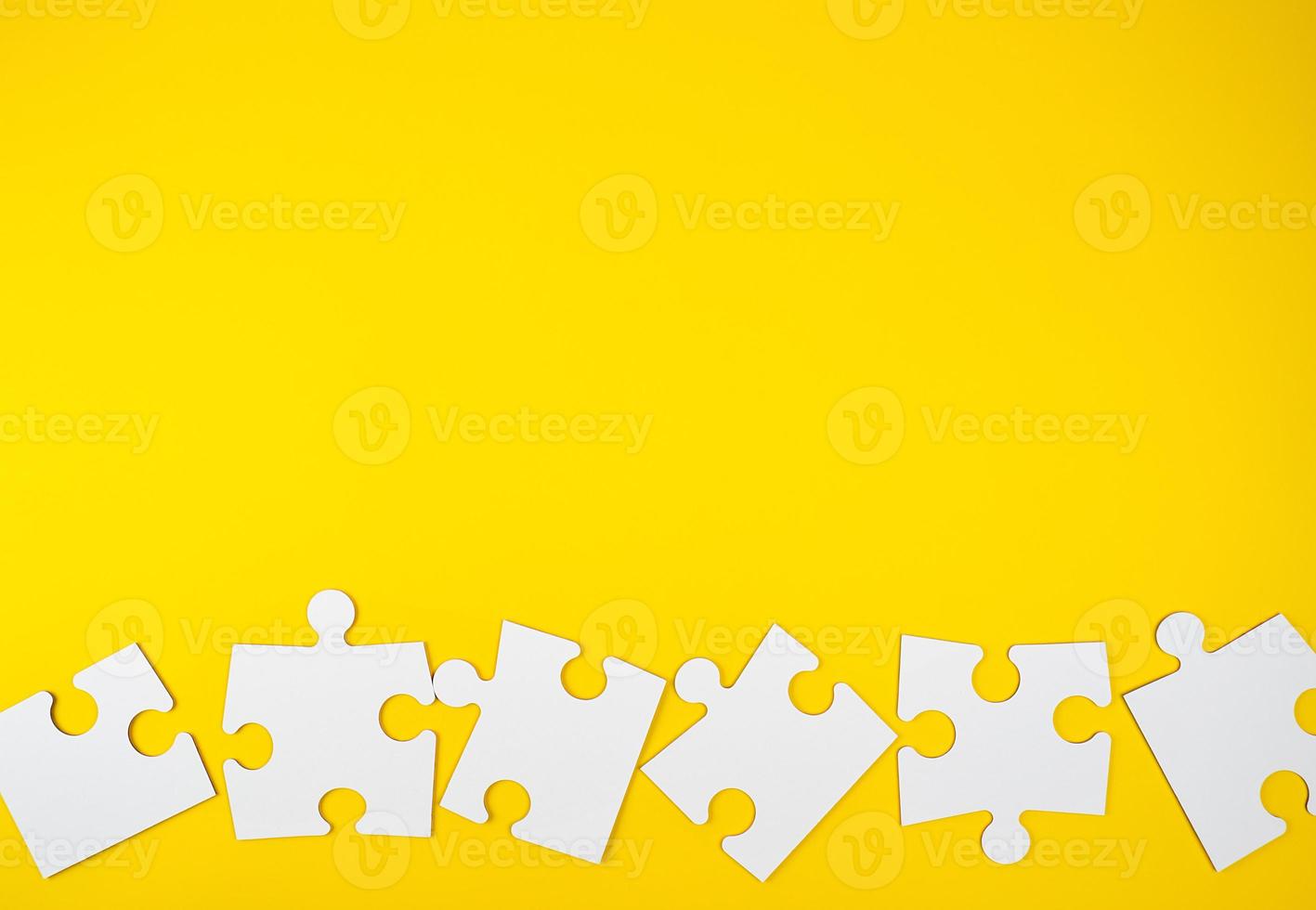 blank white big puzzles on yellow background, flat lay photo