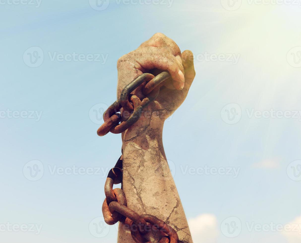 female hand is wrapped in an iron rusty chain photo