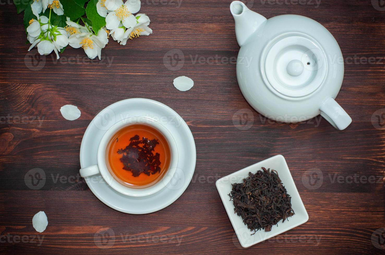 Black tea with jasmine in a white cup on a wooden table photo